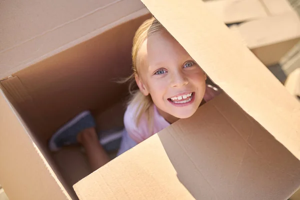 Joyful girl hiding in big box on street — Stock Photo, Image