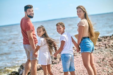 Kıyıda el ele yürüyen bir aile.