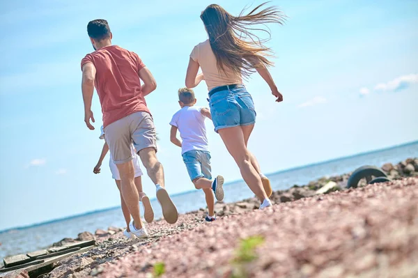 Szczęśliwa rodzina jest podekscytowana i biegnie po plaży — Zdjęcie stockowe