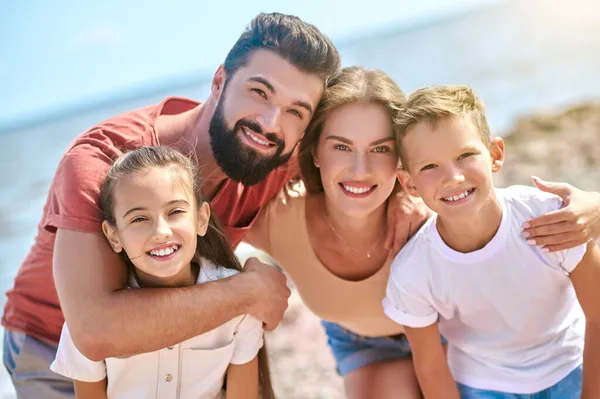 Una foto de la feliz familia sonriente divirtiéndose en una playa — Foto de Stock