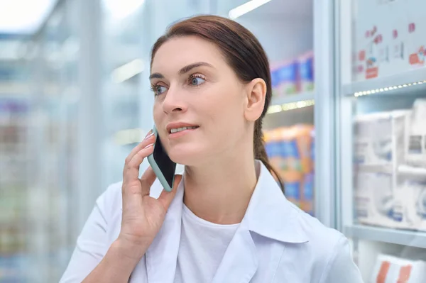 Femme amicale en blouse de laboratoire parlant sur smartphone — Photo