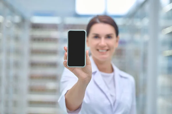 Woman in medical gown showing smartphone screen