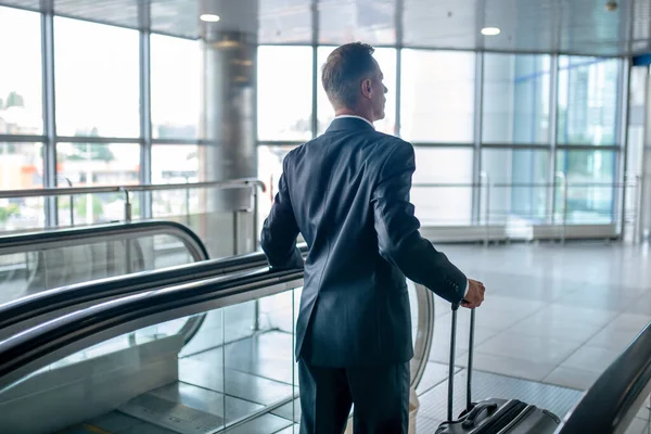 Achteraanzicht van man met koffer op roltrap — Stockfoto