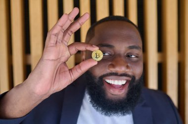 Elinde bitcoin tutan esmer sakallı bir adam.