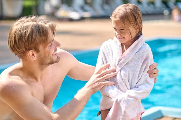 Um jovem lavando seu filho com uma toalha perto da piscina — Fotografia de Stock