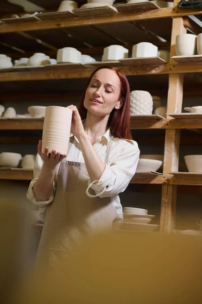Een jonge langharige vrouwelijke pottenbakker in haar werkplaats — Stockfoto