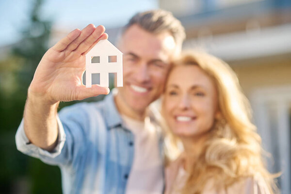 House sign in hand of man hugging wife