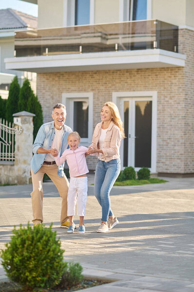 Cheerful little girl with dad and mom on street