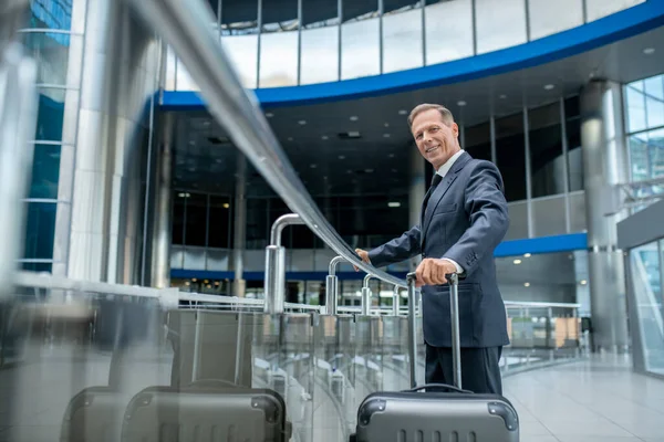 Hombre de negocios sonriente con maleta en el aeropuerto — Foto de Stock