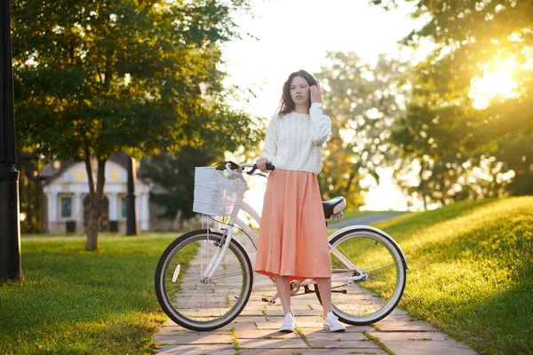 Chica joven con una bicicleta en un parque por la mañana — Foto de Stock