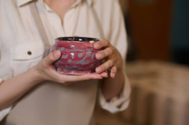 Yeni yapılmış çömlekleri elinde tutan kadın çömlekçi.