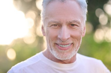 Kendine güvenen gri saçlı bir adamın resmi.