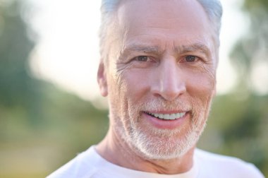 Kendine güvenen gri saçlı bir adamın resmi.