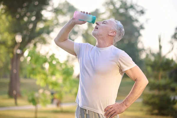 En bild på en man med en flaska vatten i händerna — Stockfoto