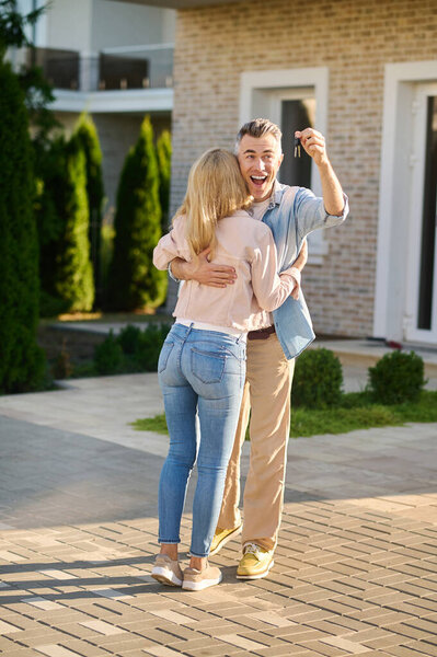 Enthusiastic man with keys hugging his wife