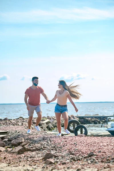 Ένα ζευγάρι κρατιέται χέρι-χέρι και τρέχει σε μια παραλία — Φωτογραφία Αρχείου