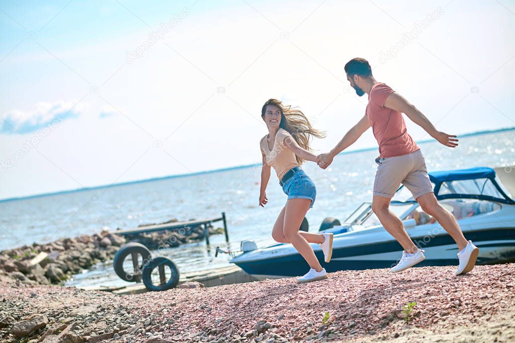 A couple holding hands and running on a beach