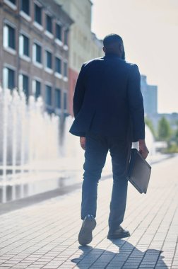 Sokakta takım elbiseli, esmer uzun boylu bir adam.