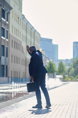 Sokakta takım elbiseli, esmer uzun boylu bir adam.