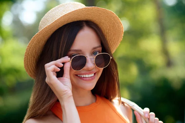 En bild på en ung kvinna i halmhatt och solglasögon — Stockfoto
