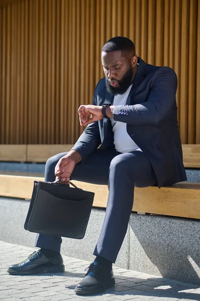 Een zwarte man zit op de bank en wacht op iemand. — Stockfoto