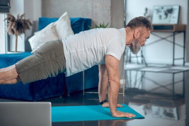 Olgun bir adam sindirim yapıyor ve şınav çekiyor.