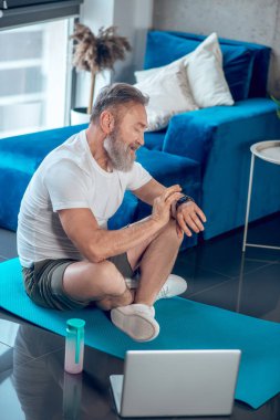 Yetişkin bir adam, antrenmandan sonra nabzını kontrol eden saate bakar.