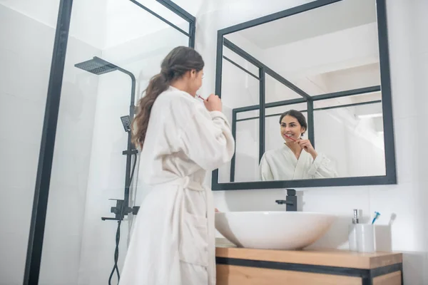 Una foto de una mujer joven en un albornoz en el baño — Foto de Stock