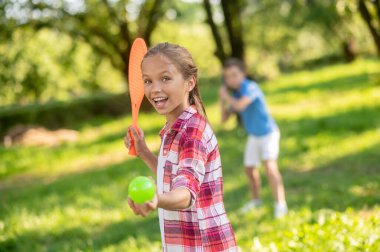 Raketli ve toplu bir kız ve tenis oynayan erkekler.