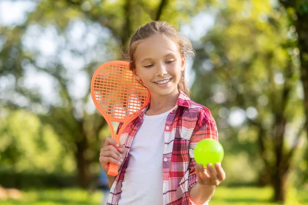 Menina sorridente com raquete de tênis e bola — Fotografia de Stock