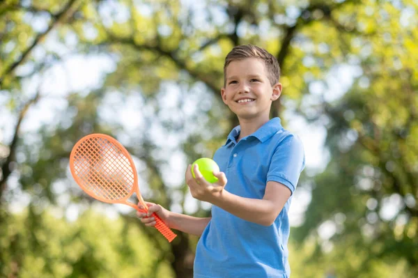 Уверенный в себе мальчик с ракеткой и теннисным мячом — стоковое фото