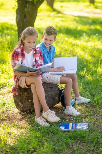 Pojke och flicka gör lektioner i park — Stockfoto