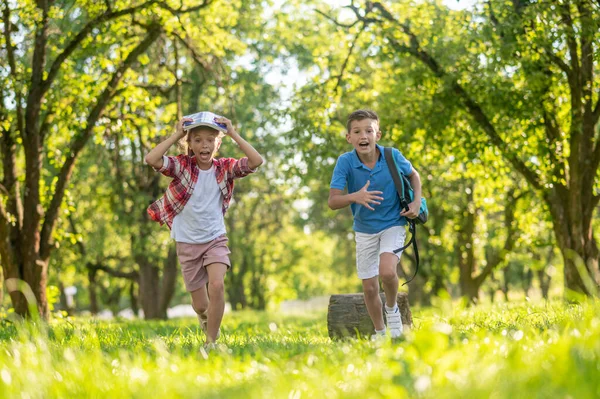 Cheerful boy and girl running in park — Stock Photo, Image