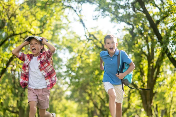 Девочка и мальчик школьного возраста бегают в парке — стоковое фото