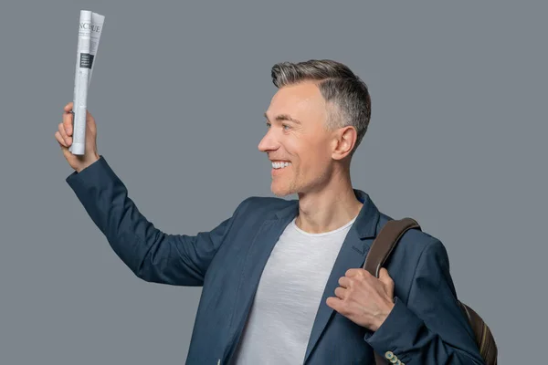 Perfil do homem sorridente com jornal levantado na mão — Fotografia de Stock