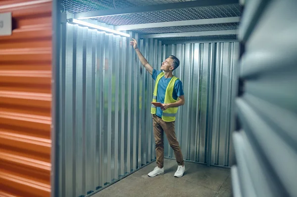 Muž kontroluje lampu zavěšenou u stropu — Stock fotografie