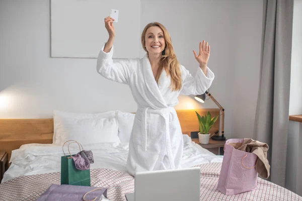 Радісна жінка з кредитною карткою на ліжку — стокове фото