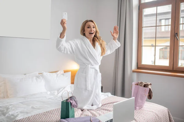Entusiastisk kvinna med kreditkort i sovrummet — Stockfoto