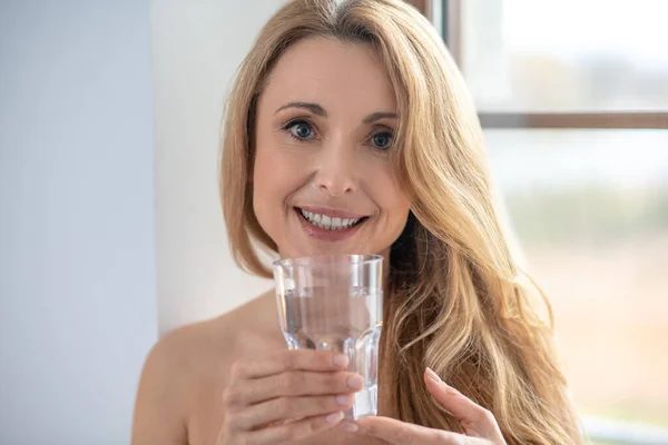 Счастливая женщина с голыми плечами и стаканом воды — стоковое фото
