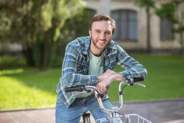 Una foto de un joven con camisa de aplaid en una bicicleta — Foto de Stock