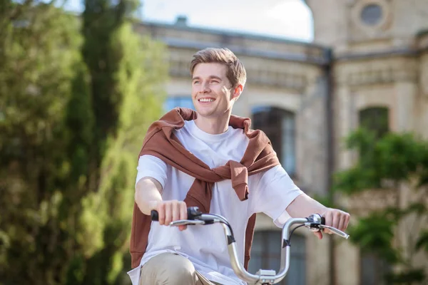 Un joven sonriente con una camiseta de ehite en una bicicleta — Foto de Stock