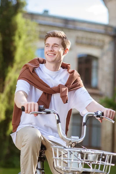 Un joven sonriente con una camiseta de ehite en una bicicleta — Foto de Stock