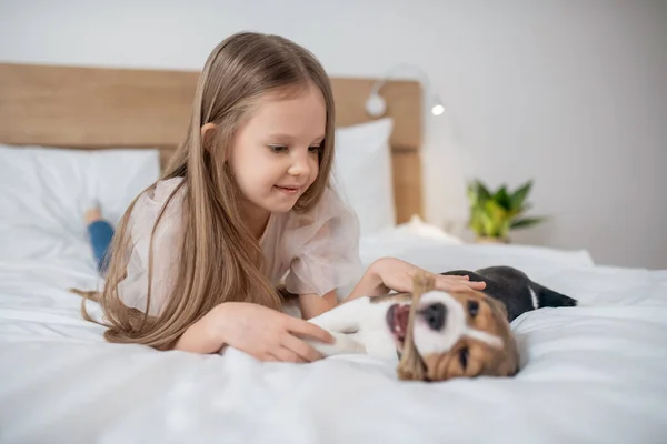 Una linda chica jugando con su cachorro y luciendo feliz —  Fotos de Stock