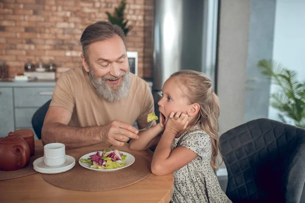 Familie frühstückt zusammen und Papa versucht, seinen Dolch zu füttern — Stockfoto