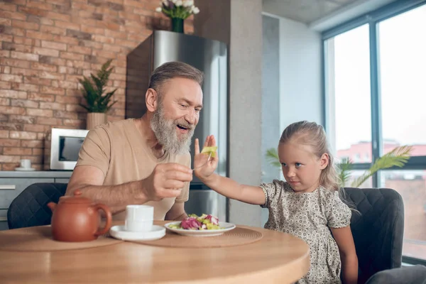 Familia desayunando juntos y papá tratando de alimentar su daghter —  Fotos de Stock