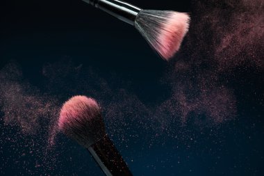 Professional black make-up brush with pink powder in motion isol clipart