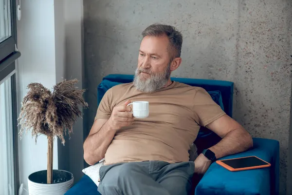 Un hombre tomando su café de la mañana y luciendo relajado — Foto de Stock