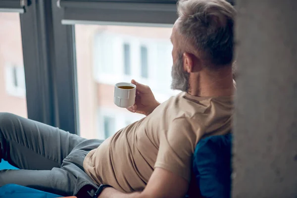 Egy férfi, aki a reggeli kávéját tölti, és nyugodtnak tűnik. — Stock Fotó