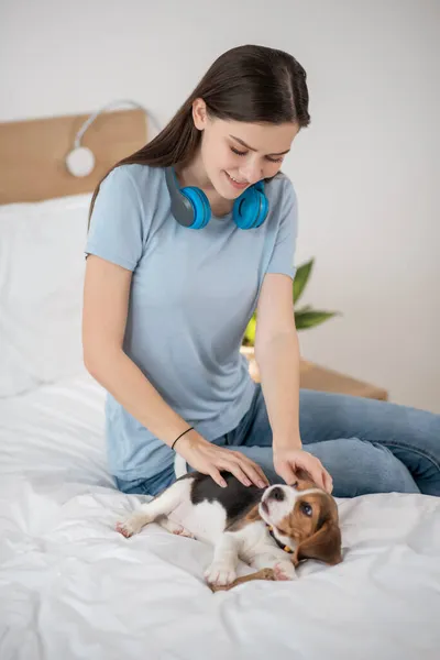 En husdjursägare sitter på sängen och fäller nöjd med sitt husdjur — Stockfoto