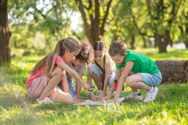 Niños con mapa y lupa en el césped — Foto de Stock